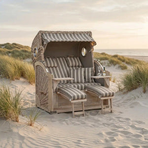 Gartenstrandkorb Comfort 500 Plus aus Mahagoni mit antik-weißem Kunststoff-Rundgeflecht und seitlichen Bullaugen, 3/4-Liegemodell im XL-Format mit taupefarbenem Stoff.
