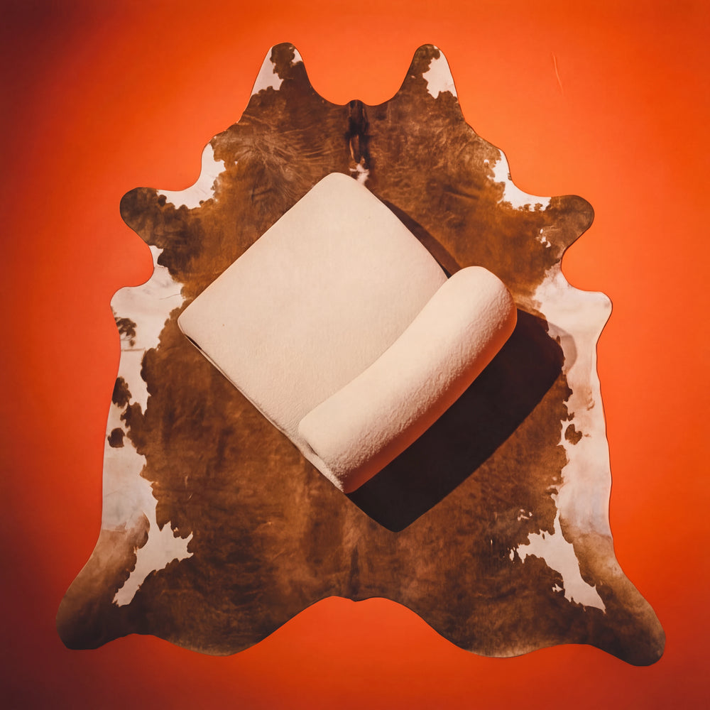 Polstermöbel Dresden – Weißer Bouclé-Sessel Vogelperspektive auf Kuhfell-Teppich vor orangeroter Wand, Möbel Graf Pirna