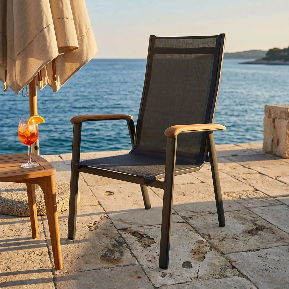 Moderner Stapelstuhl Reno mit Aluminiumgestell, Teak-Armlehnen und anthrazitfarbener Textilene-Bespannung für den Außenbereich